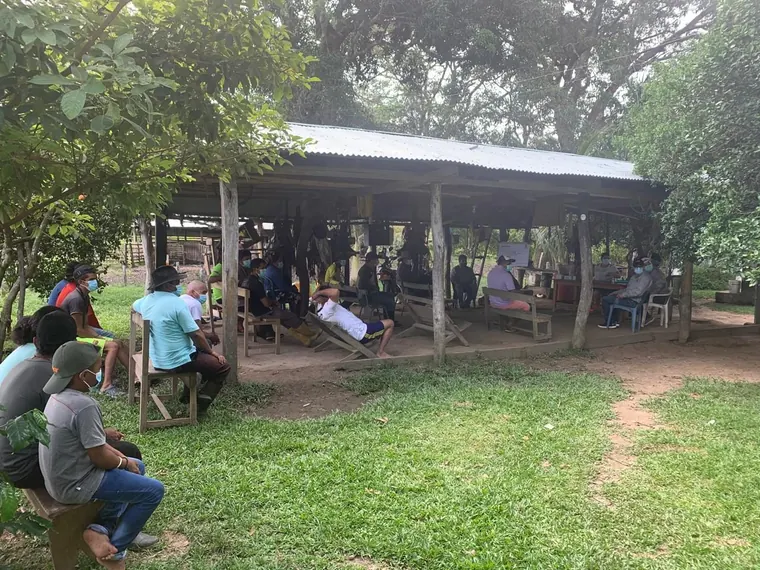 Reunión comunitaria de PBCM bajo enramada